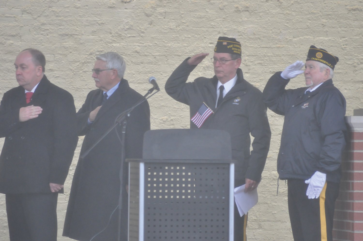Marc Gabel, center, commander of Brian Bowman VFW Post 1431, salutes during the playing of Taps, flanked by Mayor Todd Barton, Mike Whitacre and Post 72 third vice commander Mike Spencer.