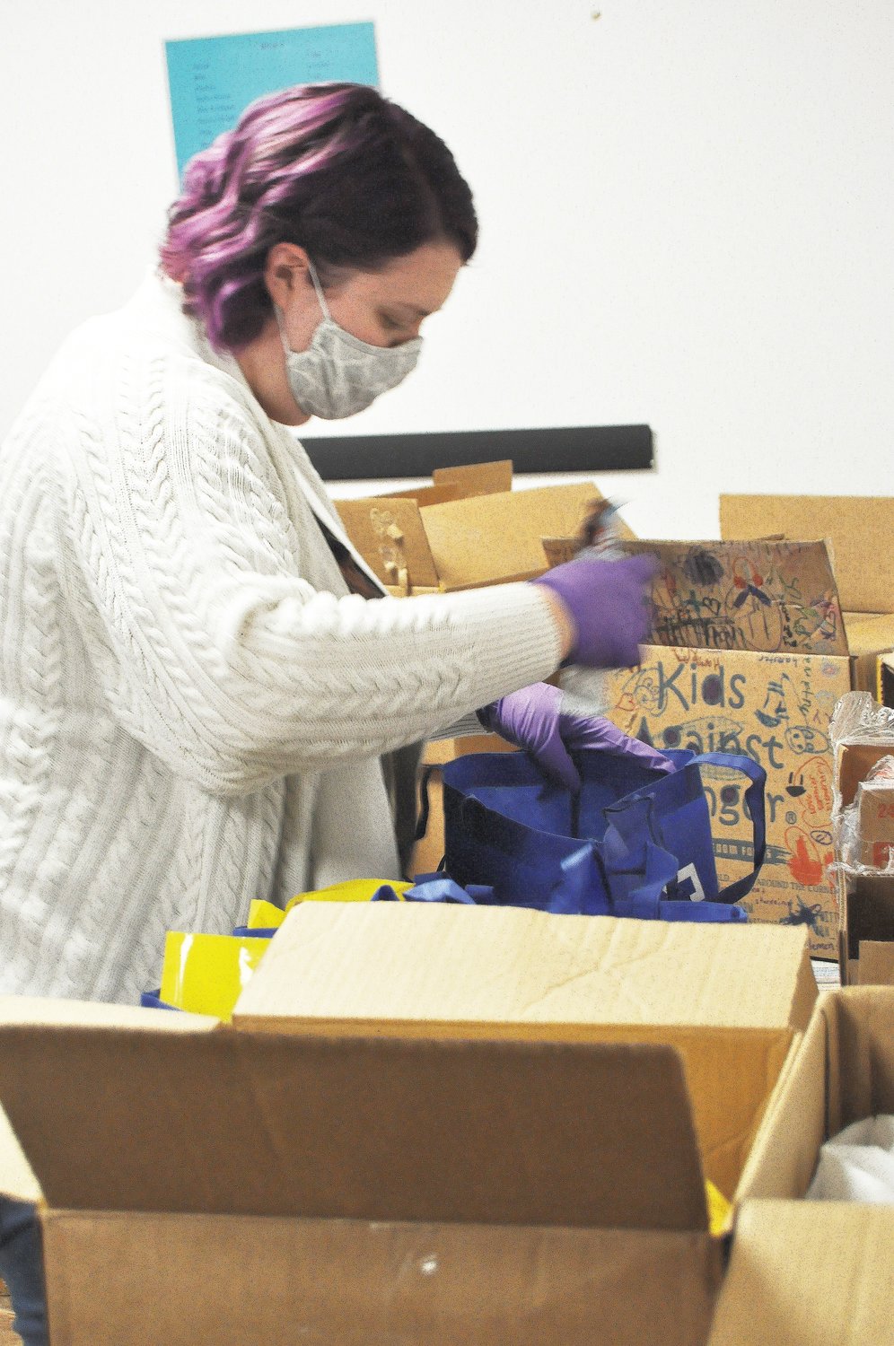 Kelsey Norris packs a bag of food for the Nourish program Thursday at the Montgomery County Youth Service Bureau. Norris and her husband, Matt, the daughter and son-in-law of Youth Service Bureau Executive Director Karen Branch, volunteered to pack this week's shipment to relieve employees who have done the packing since the offices closed due to the COVID-19 outbreak.