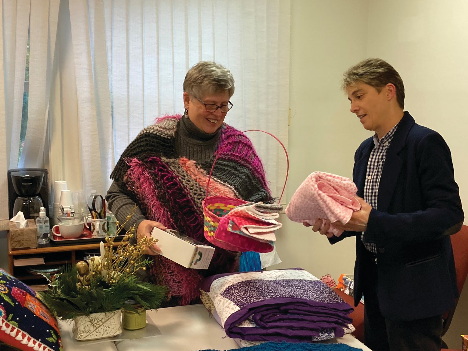 j Miranda, right, folds a blanket for a gift basket held by Cheryl Fuhrmann for Dusk-to-Dawn Bereavement Services’ Harvest Festival on Nov. 6.
